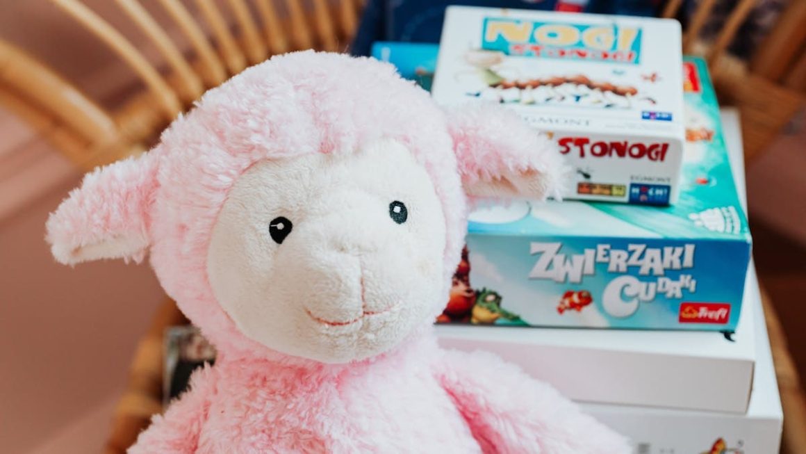 Close-up of a pink plush lamb alongside colorful board games, perfect for children's playrooms.